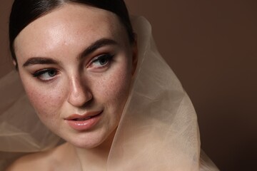 Fashionable portrait of beautiful woman with fake freckles on brown background, closeup