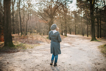 Fototapeta premium Woman walking in the forest on a cold autumn day
