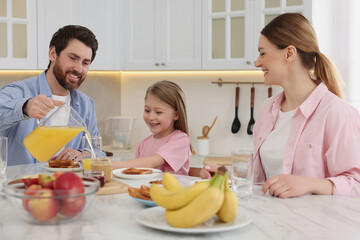 Happy family having breakfast at table in kitchen