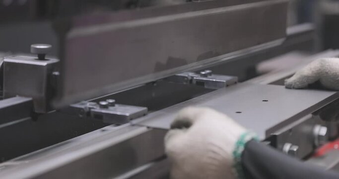 A worker bends a metal part in a machine. Hydraulic sheet metal bending machine. Metal processing