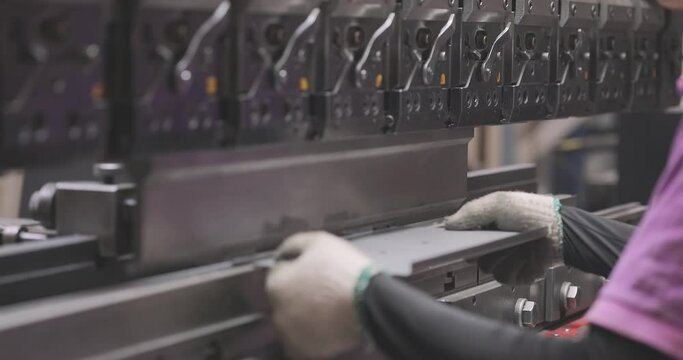 A worker bends a metal part in a machine. Hydraulic sheet metal bending machine. Metal processing
