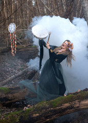 Wild Woman Playing Shamanic Drum Standing On Green Moss Tree Trunk In Forest, White Smoke Bomb