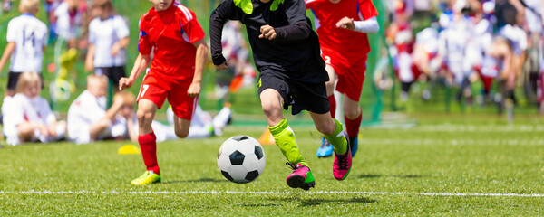 Obraz premium Group of Children Playing Soccer Football League Game. A Player Running Fast With a Soccer Ball Toward the Goal Ready To Kick the Ball and Score. Kids Compete in a Football Tournament on a Grass Pitch