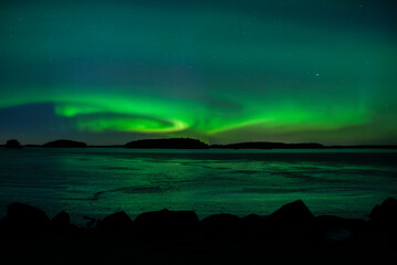 Northern lights dancing over frozen lake in Farnebofjarden national park in north of Sweden.