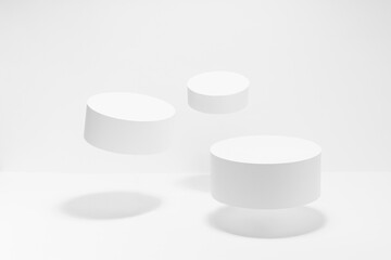 Set of three round white pedestals mockup for cosmetic products, tilt, fly in hard light, shadow on white background. Scene for presentation skin care products, gifts, advertising in elegant style.