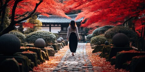 A girl walking in a Japanese temple garden in Kyoto. Autumn fall season, with red maple leafs.