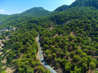 Aerial view of green volcanic mountain landscape with modern high-quality serpentine road in southern Turkey. Drone flies over beautiful scenery of mountain ranges and serpentine.