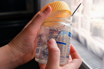 Woman checking label of empty peanut butter jar. Ingredient control, nutritional values, fat,...