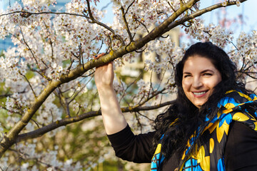 Attractive young ukrainian woman smiling in blooming cherry orchard in spring