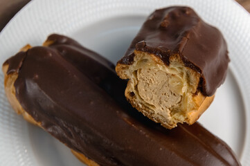 French ecler with chocolate on white plate. Traditional french dessert eclair.