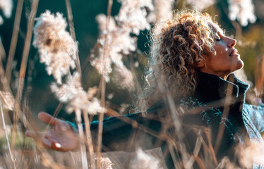 One happy and free woman outstretching arms in golden field of high grass. Concept of healthy lifestyle and wellbeing. Joyful people in outdoor leisure activity. Nature lover female lady enjoying life
