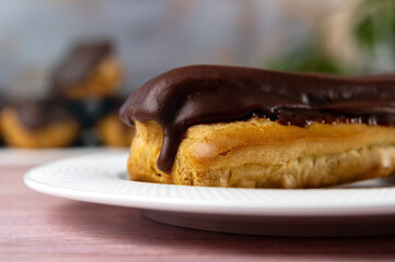 French ecler with chocolate on white plate. Traditional french dessert eclair.