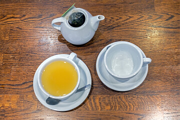 ginger tea in a cup next to the teapot on the table. View from above