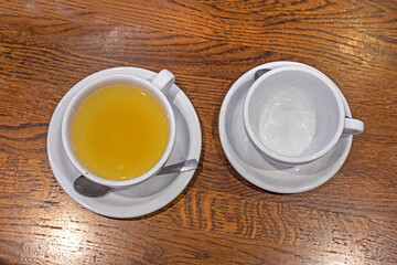 two cups of ginger tea and an empty one next to the teapot on the table.