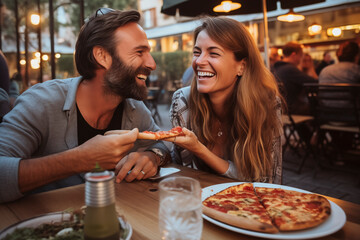 Happy young adult couple have fun eating a pizza together outdoor in traditional italian pizzeria restaurant sitting and talking and laughing. People enjoying food and dating relationship. Tourists - obrazy, fototapety, plakaty
