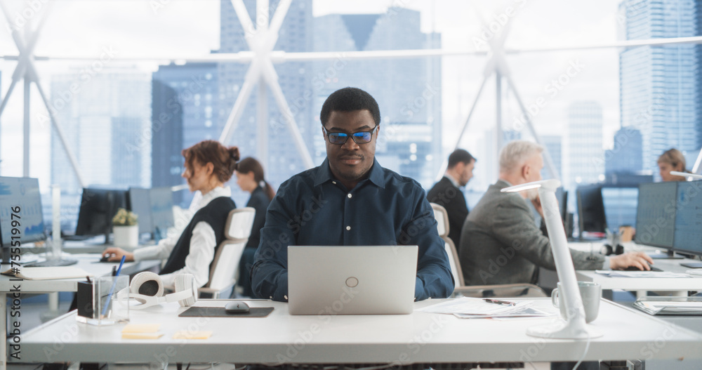 Poster Succesful Black Man Typing On Laptop Computer In Bright Scyscraper Office With Diverse Employees In Downtown. Cheerful Male Programmer Coding In Modern Fintech Startup Workspace, Engineering Software