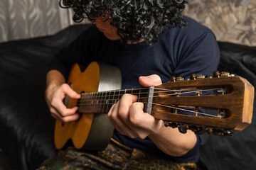 Playing acoustic guitar. The musician clamps the frets of the guitar on the neck. Musical...