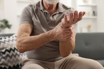 Arthritis symptoms. Man suffering from pain in wrist at home, closeup