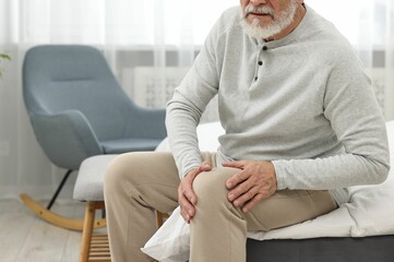 Arthritis symptoms. Man suffering from pain in knee at home