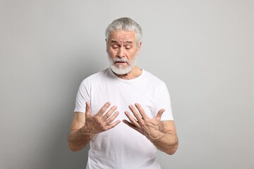 Arthritis symptoms. Man suffering from pain in hands on gray background