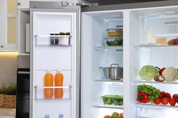 Open refrigerator full of different products in kitchen