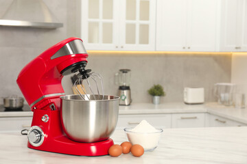 Modern red stand mixer, eggs and bowl with flour on white marble table in kitchen, space for text
