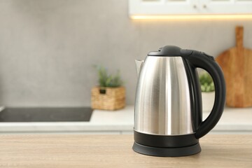 Modern electric kettle on table in kitchen. Space for text