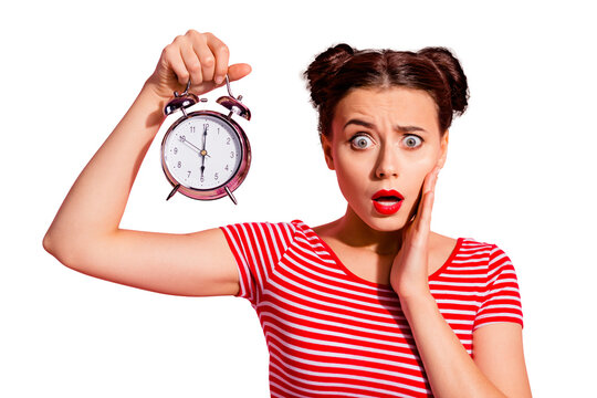 Close-up portrait of her she nice cute charming winsome lovely attractive worried girl wearing striped t-shirt holding showing clock oops omg isolated over pink pastel background