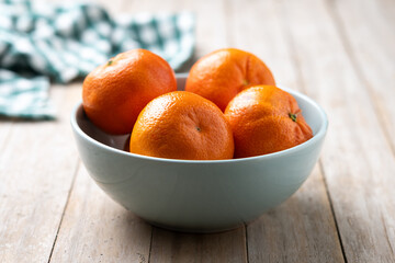 Fresh tangerines in green bowl on wooden table
