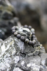 Bangle made from natural black stones for men or female fashion, outside on the rocks. Handcraft precious item. Jewelry accessories.