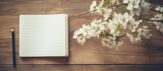 A vintage toned photograph showing a white cherry blossoms tree in spring next to an open notebook and a pen on a wooden table. The notebook is empty, waiting to be filled with thoughts and ideas.