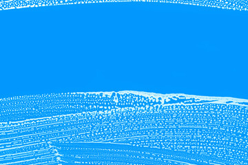 soap foam waves on window glass with one clear wiped strip, blue and white abstract background texture