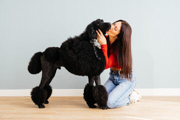 Beautiful Woman Sharing an Affectionate Kiss With Her Black Poodle Indoors