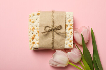 Matzo and flowers on pink background, top view