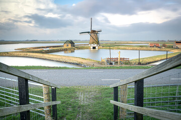 Polder view of Wadden Sea island Texel with windmill and some rainy clouds moving over typical Dutch landscape - 755550706