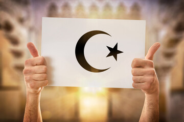 Hands okay holding a poster with islamic symbol in mosque