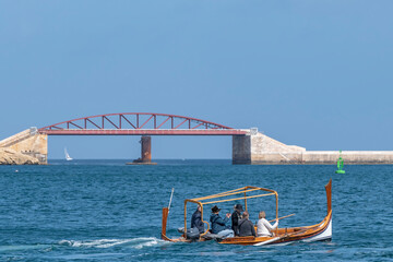 A typical traditional Maltese wooden boat, with St Elmo's Bridge in the background, Valletta, Malta