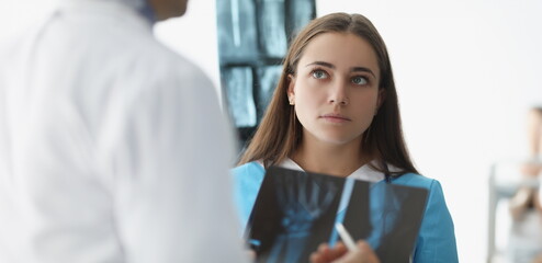 Obraz premium Woman doctor communicating with colleague with xrays in clinic. Teamwork in medicine concept