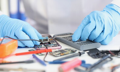 Master repairman inserting microchip into mobile phone closeup. Cell phone repair and service...