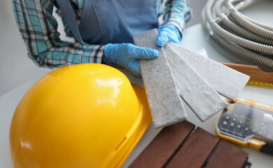 Builder holding gray tiles for bathroom in workshop closeup. Apartment decoration concept