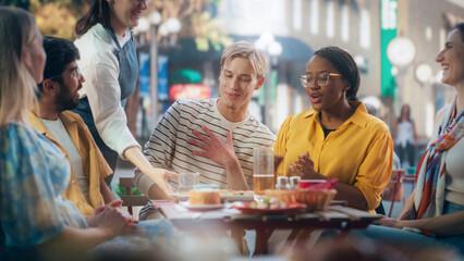 Young Talented Colleagues Enjoying a Work Break in a Cafe. Waiter Bringing a Delicious Italian Pizza. Young Men and Women Having Fun Conversations on a Terrace, Enjoying Tasty Food and Beverages