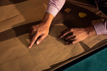 Close up of fale fashion tailor hands working on the measurements for the suit design in his workshop. © Zoran Zeremski