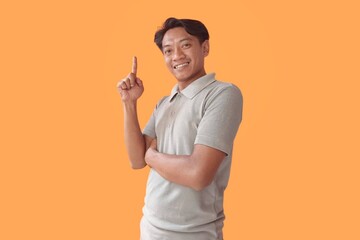 Handsome Asian man standing over orange background pointing fingers to camera with happy and funny face. good energy and vibes.