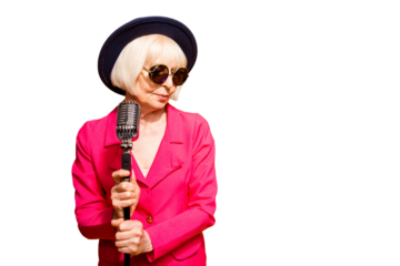 Portrait of grandmother in a hat and red jacket holds a microphone stand and looks sideways isolated on brigth yellow background with copy space