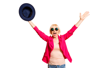 Party mood! Portrait of old woman stretching her arms upwards waving her hat celebrating the victory isolated on vivid yellow background