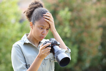 Worried black photographer is checking bad result on camera