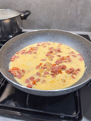 an omelet with sausage is fried in a pan