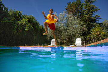 Joyful teenager jump with duck float in backyard, mid-air shot