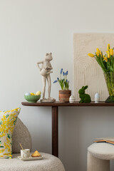 Spring and easter composition of living room interior with mock up poster frame, pouf, flowers,...