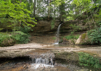 Forest waterfall in southern Swabia. Riedbach - small river in Allgäu. Small waterfall in rocky ravine with green trees around. © andrbk